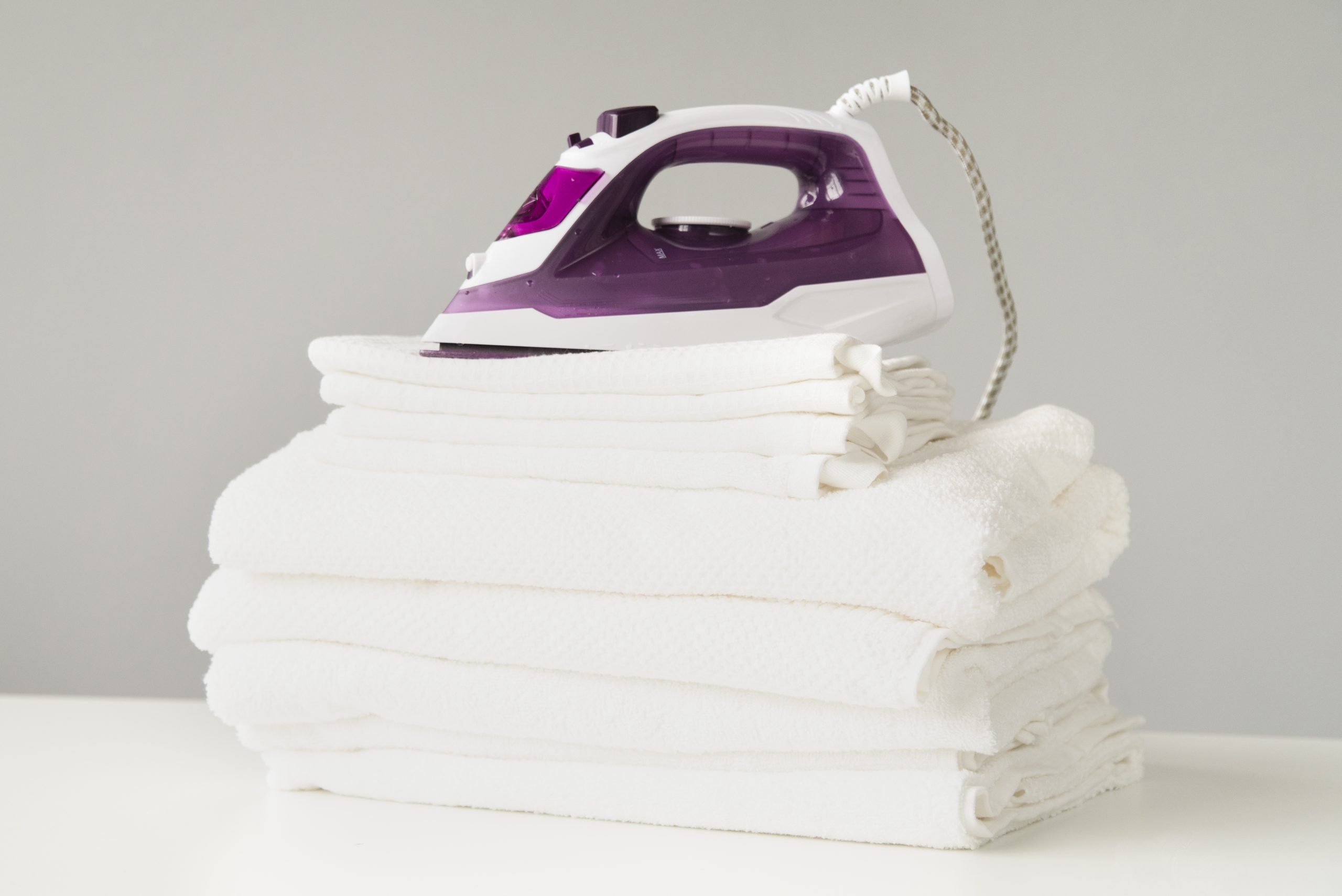 front-view-pile-towels-with-iron Bügelservice in Hamburg